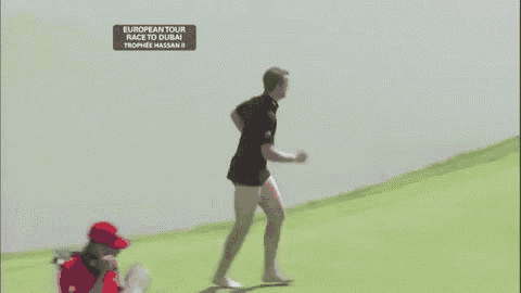 a group of men are standing on a golf course . one of the men is wearing shorts .