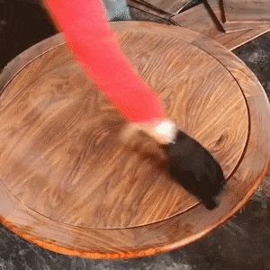 a person is painting a wooden table with a red paintbrush