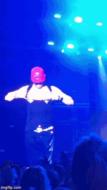 a man in a red hard hat is dancing on a stage in front of a crowd