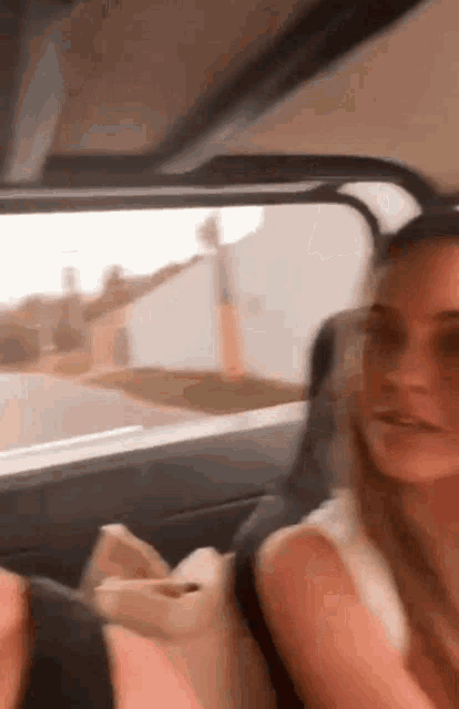 a woman is sitting in the back seat of a car talking to another woman .