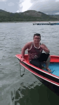 a man is sitting in a boat on a lake .