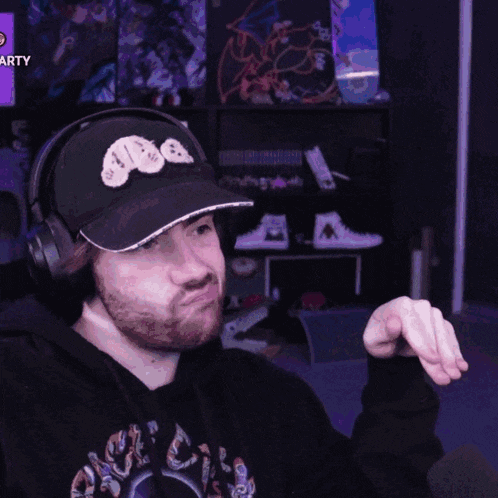 a man wearing headphones and a hat with a bear on it is pointing
