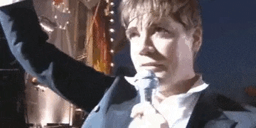 a man in a suit is holding a microphone in his hand and crying .