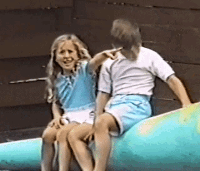 a boy and a girl are sitting on a blue whale