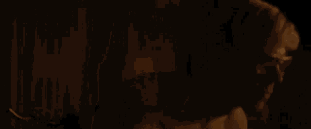 a naked man 's back is shown in a dark room in a close up .