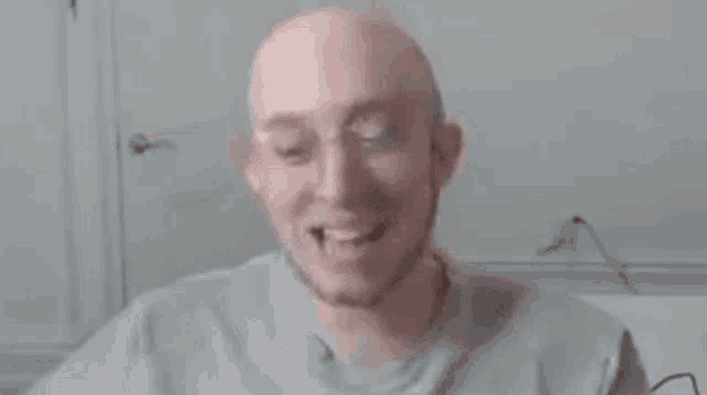 a bald man with glasses and a beard is smiling and looking at the camera .