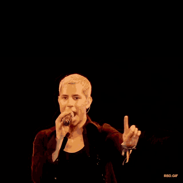 a man singing into a microphone with a black background