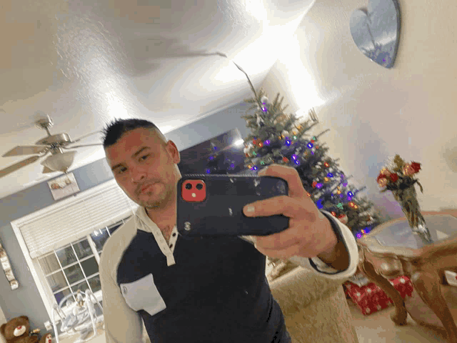 a man taking a selfie with a christmas tree in the background