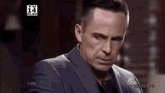 a man in a suit is making a funny face while sitting down .