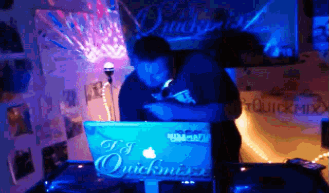a man sitting at a table with a laptop that says ' dj quickmix ' on it