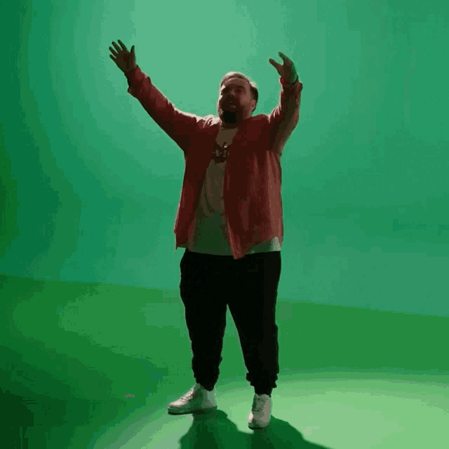 a man with his arms outstretched in front of a green background