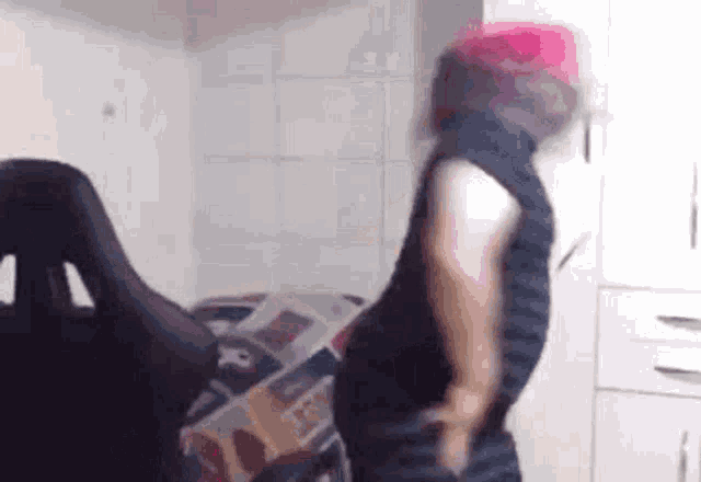 a person with pink hair is dancing in front of a computer chair .