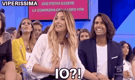 a man and a woman are sitting in front of a screen that says io ?