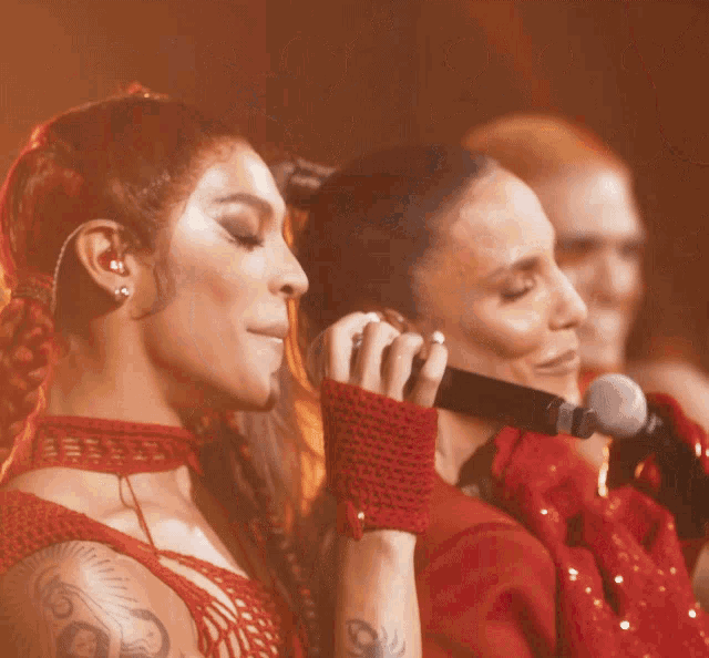 a woman singing into a microphone while wearing red