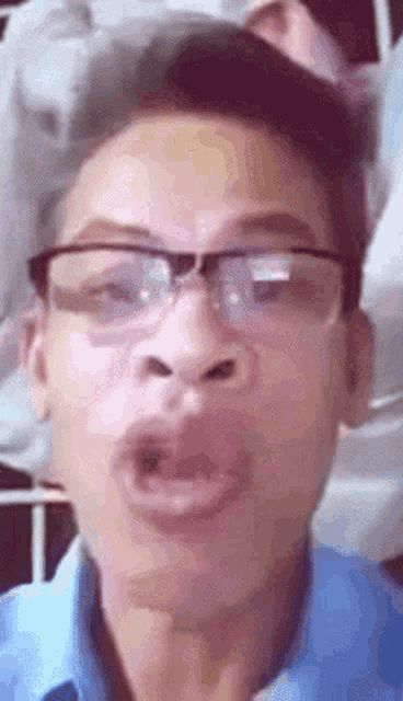 a man with glasses and a blue shirt is making a funny face