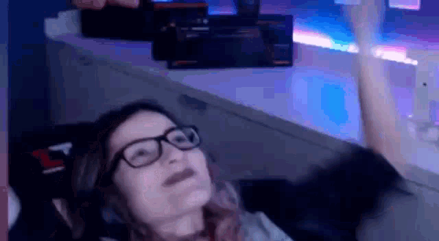 a woman wearing glasses and headphones is sitting in front of a computer screen .