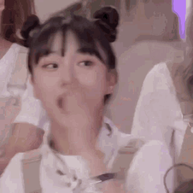 a close up of a girl with two buns on her head making a funny face .