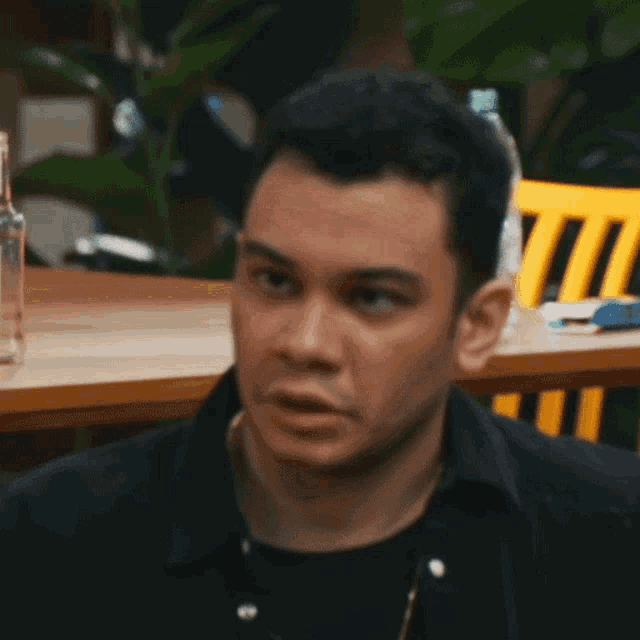 a man is making a funny face in front of a table .
