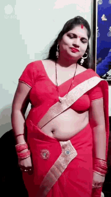 a woman is wearing a red saree and a red top .