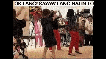 a group of women are dancing together in a room with a crowd watching .