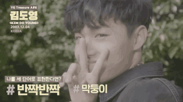 a young man making a peace sign in front of a sign that says ' yg treasure # 6 kim do young '
