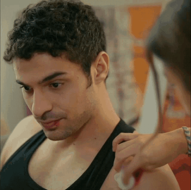 a man in a black tank top is being examined by a doctor
