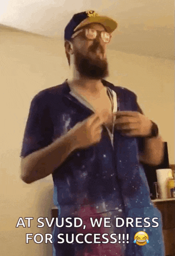 a man with a beard and glasses is wearing a blue shirt that says " at svusd we dress for success "