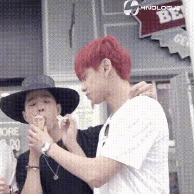 two men are standing next to each other eating ice cream cones .