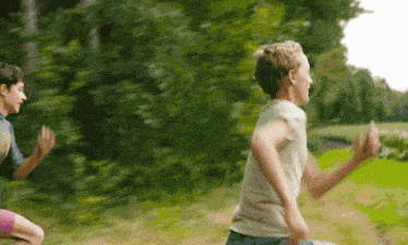 a boy and a girl are running through a field .
