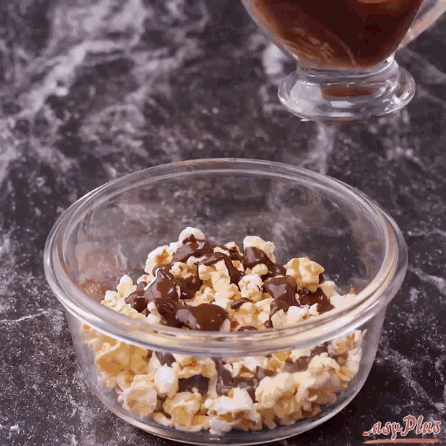 a glass bowl filled with popcorn and chocolate sauce with the words easy plus on the bottom