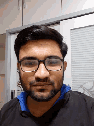 a man with glasses and a beard is looking down