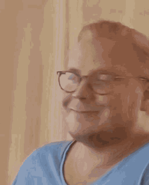a close up of a man wearing glasses and a blue shirt .