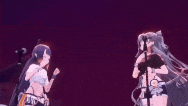 two anime girls are dancing on a stage with stuffed animals behind them .