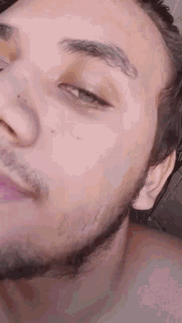 a man with a beard is taking a selfie with his eyes closed .