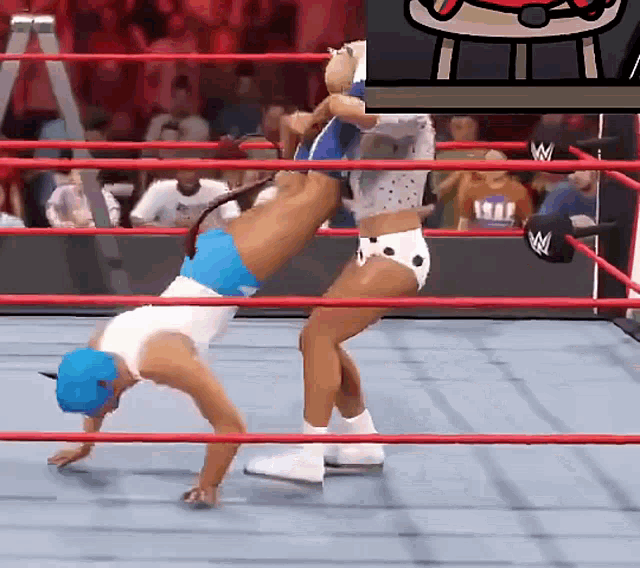 a woman in a blue hat is doing a handstand in a wrestling ring with a w logo in the background