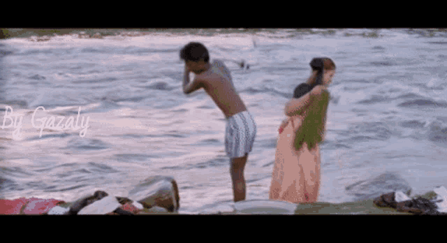 a man and a woman are standing in the water with gazaly written on the bottom right