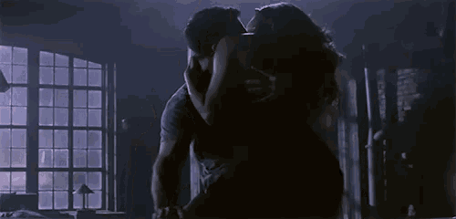 a man and woman are kissing in a dark room
