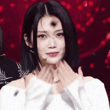 a woman with short black hair is wearing a white off the shoulder sweater
