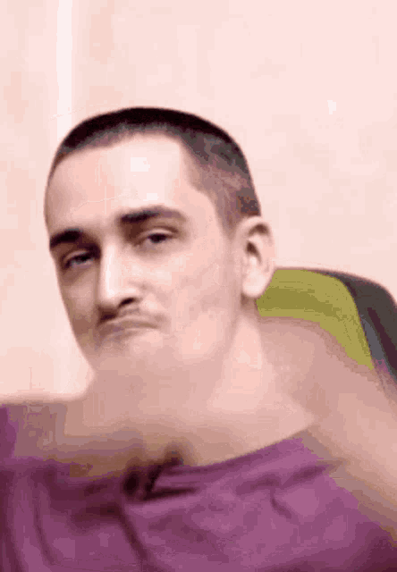a man in a purple shirt is making a funny face .