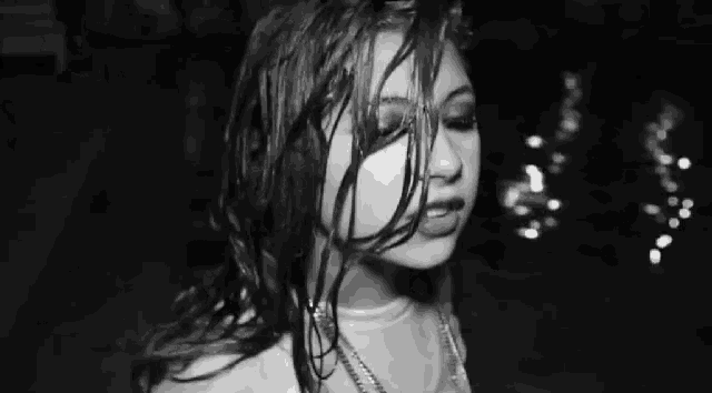 a black and white photo of a woman with wet hair and a necklace .