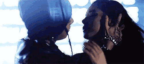 two women are kissing each other in a dark room .