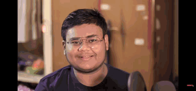 a man wearing glasses and a black shirt smiles at the camera