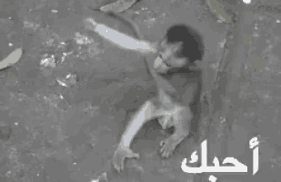 a black and white photo of a man holding another man in a puddle of water .