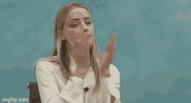 a woman is covering her face with her hands in front of a blue background .