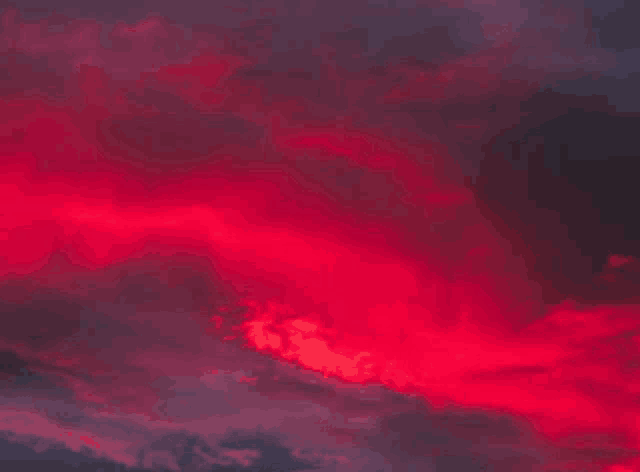 red clouds in a dark sky at sunset .