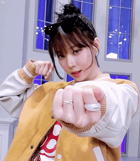 a woman wearing a yellow jacket and a white ring with the letter r on it
