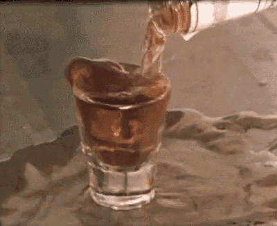a person is pouring a shot of whiskey into a shot glass .