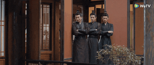 three men standing in front of a building with a wetv logo