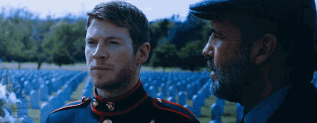 a man in a military uniform stands next to another man in a cemetery