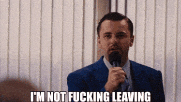a man in a suit and tie is holding a microphone and says i 'm not fucking leaving